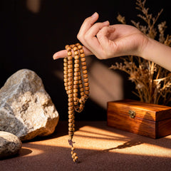 The multi-layer sandalwood bracelet dangling from a finger, highlighting the harmony and alignment of its square beads.