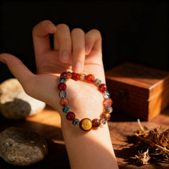 Holding the blue and red glass ‘Sacred Echo’ bracelet in hand, a BodhiPulse tool for grounding in the present moment and listening to your inner voice.