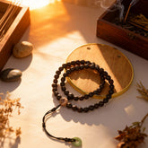 The Inner Flame mala on a table, light highlighting the texture of soapberry, agate, and jade beads, symbolizing quiet depth and stored strength.