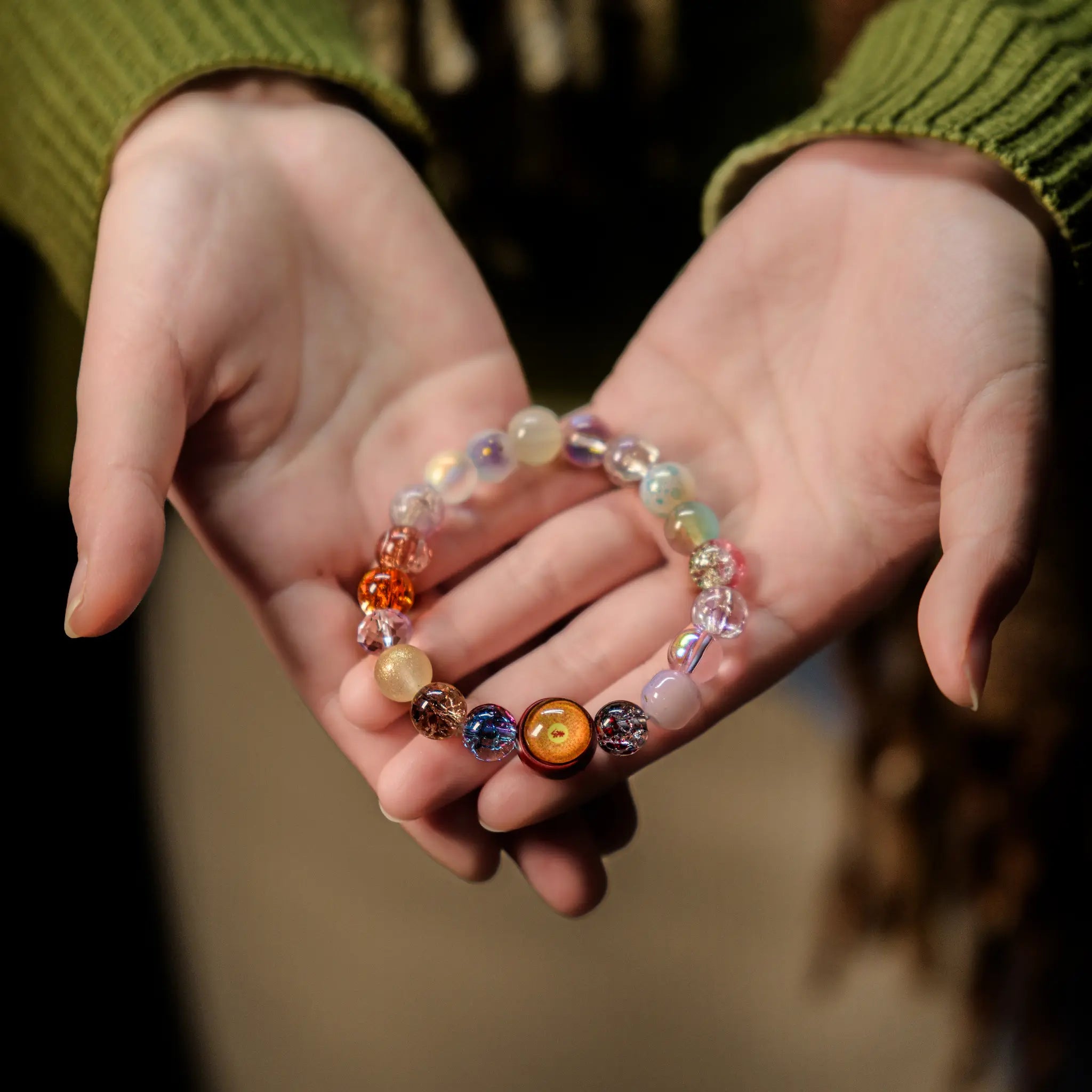 Gently cupping the vibrant multicolor bracelet in both hands, symbolizing receptivity to the flow of good fortune and healing energy with BodhiPulse.