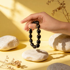 Handmade 12-bead ancient lotus seed bracelet (mala) shown dangling, made from natural materials for spiritual practice