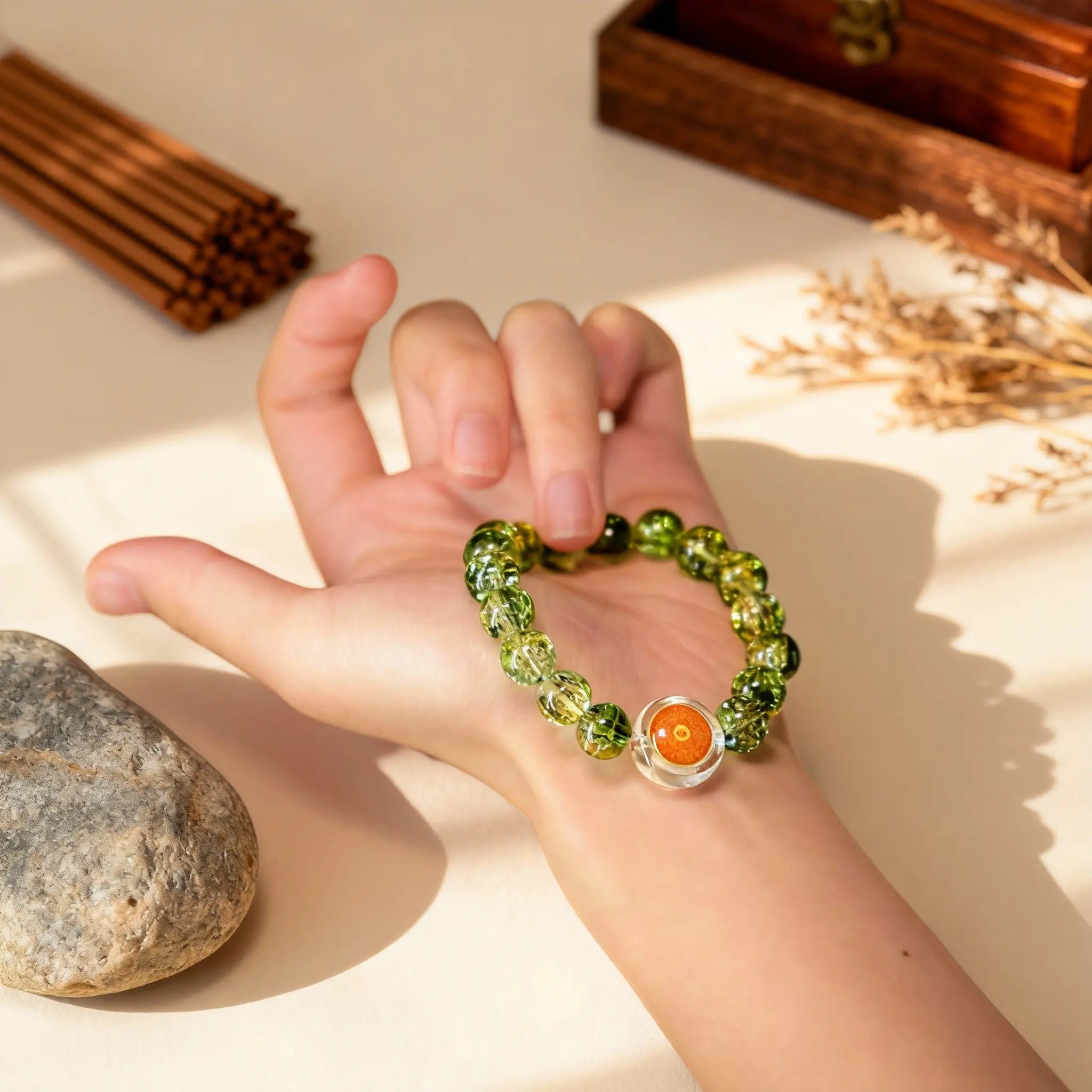 Holding the BodhiPulse green glass meditation bracelet in hand, a tool for zen in the present moment and channeling temple energy.